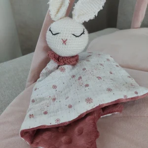 Une image d'un doudou couverture lapin de face, sur un fond rose